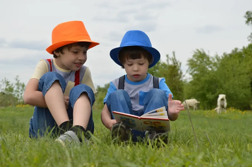 Deux jeunes garçons en salopette et chapeaux colorés lisant un livre ensemble