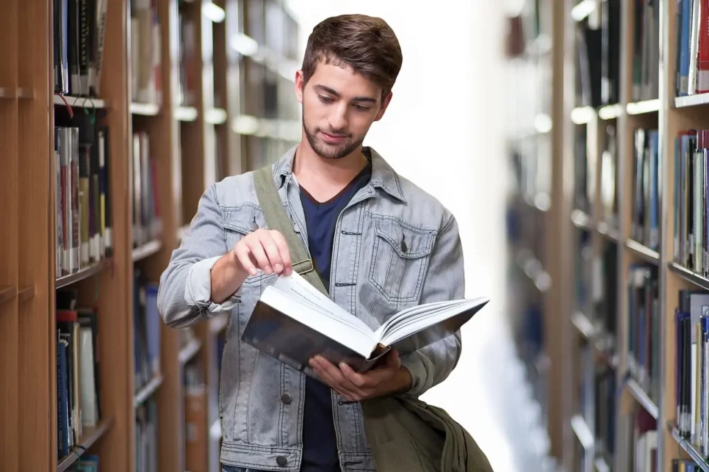 Étudiant dans une bibliothèque lisant un livre ouvert